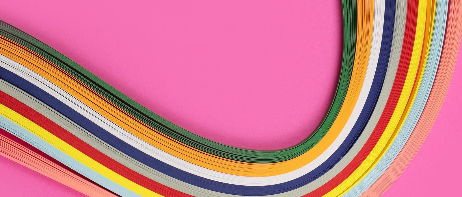 Colorful quilling, twisting paper, abstract rainbow on pink background.