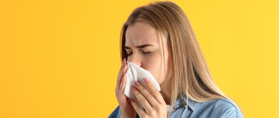 A close up of a student sneezing into a tissue