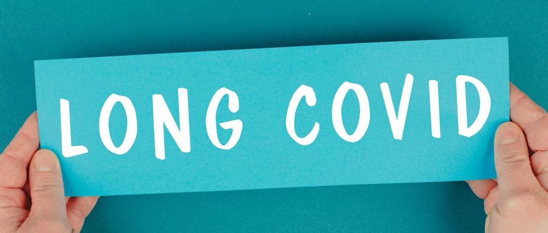 The words Long COVID on blue rectangular paper held by male hands.