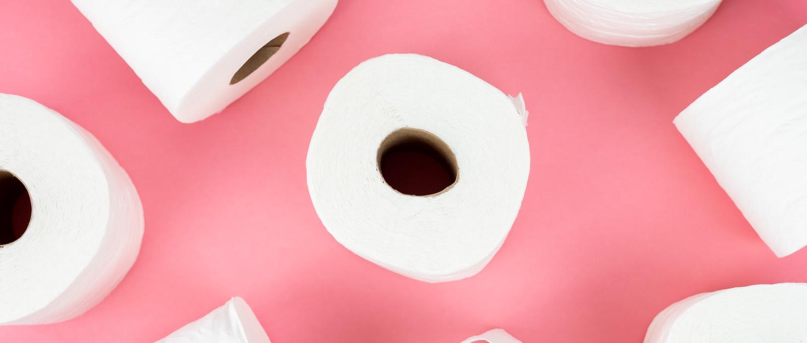 Several rolls of toilet roll on a pink background.
