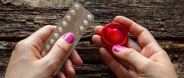 A woman holding the contraceptive pill and a red condom
