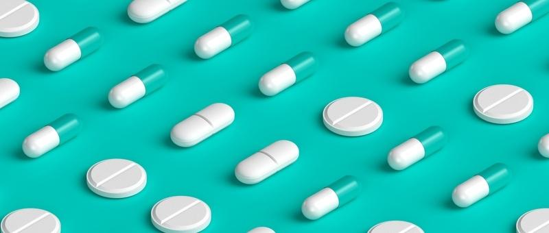 Assorted white pill-form and tablet medicines against blue background.